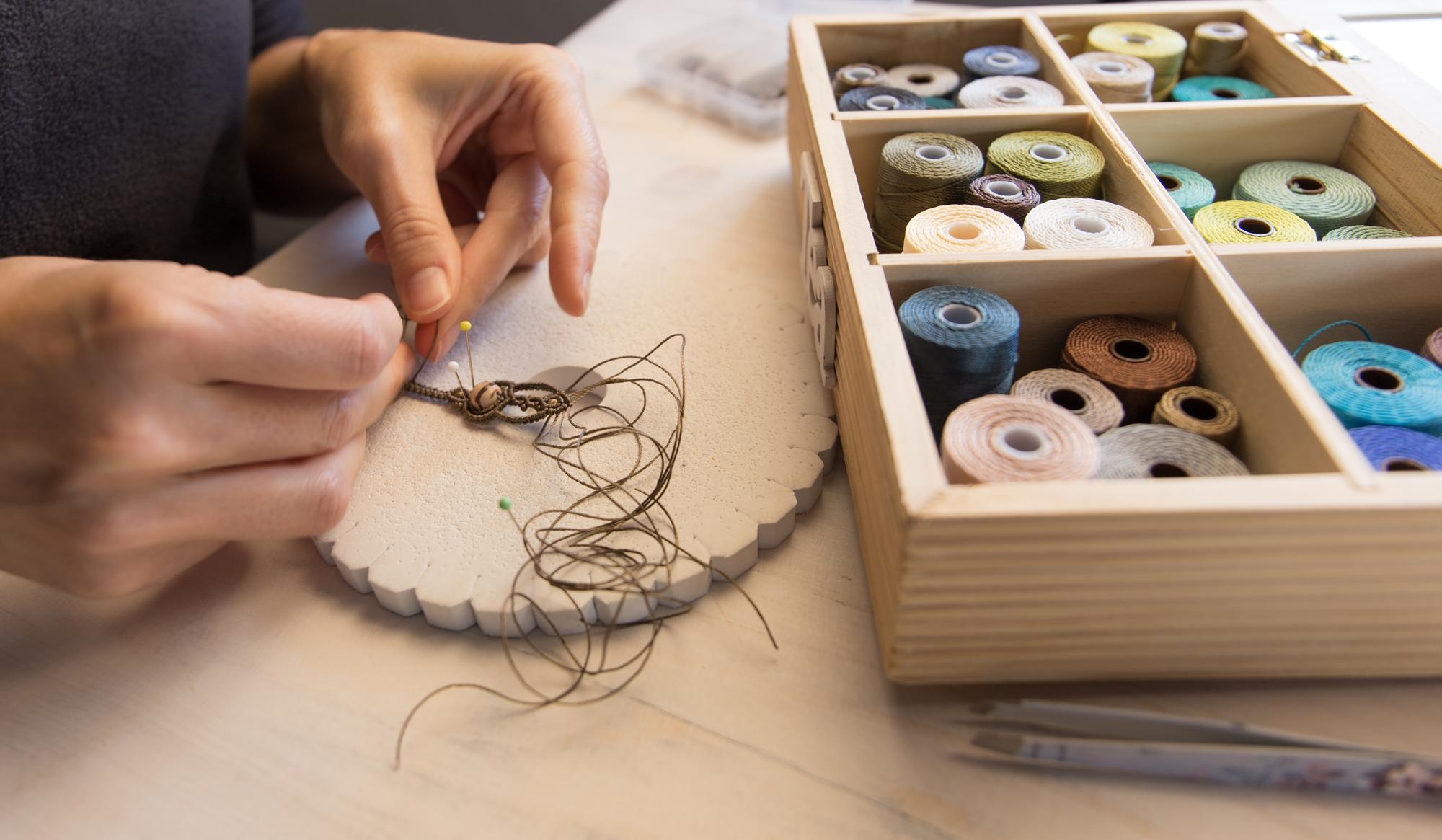 embroiderer working at a table with threads